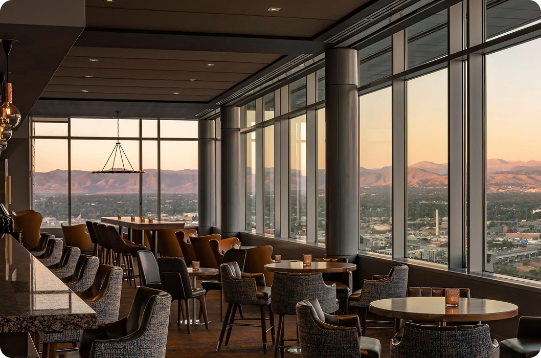 Spacious lounge with large windows showcasing a sunset view of distant mountains. Elegant seating and soft lighting create a warm, inviting atmosphere. Spacious lounge with large windows showcasing a sunset view of distant mountains. Elegant seating and soft lighting create a warm, inviting atmosphere.